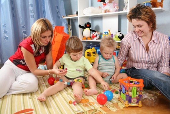 two mothers play with children in playroom two mothers play with children in playroom