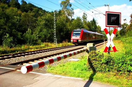 Zug nähert sich einem Bahnübergang mit geschlossener Schranke