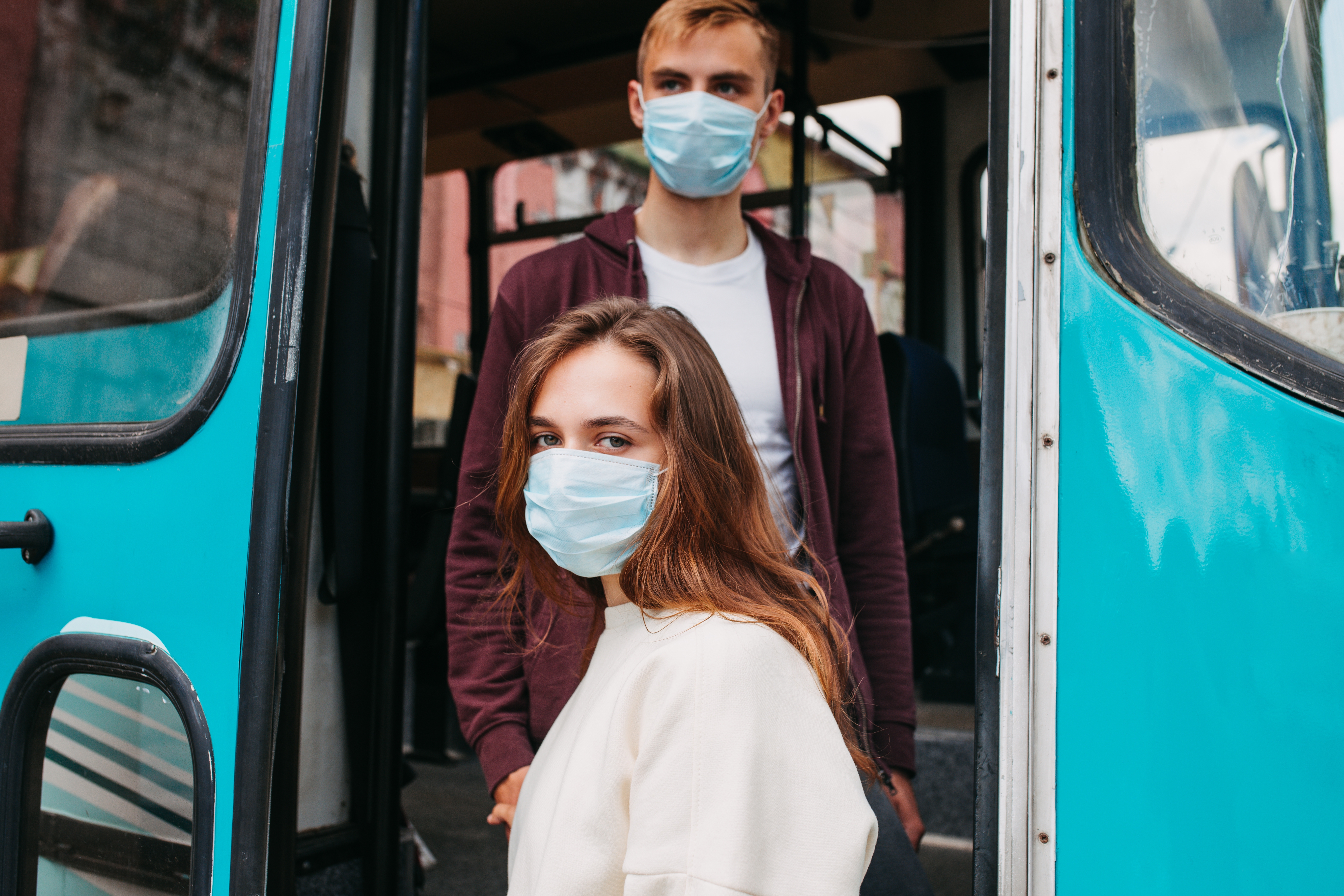 young couple with respiratory masks traveling in the public transport by bus