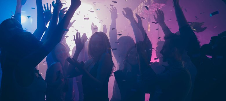Close up photo of many party people dancing purple lights confetti flying everywhere nightclub event hands raised up wear shiny clothes