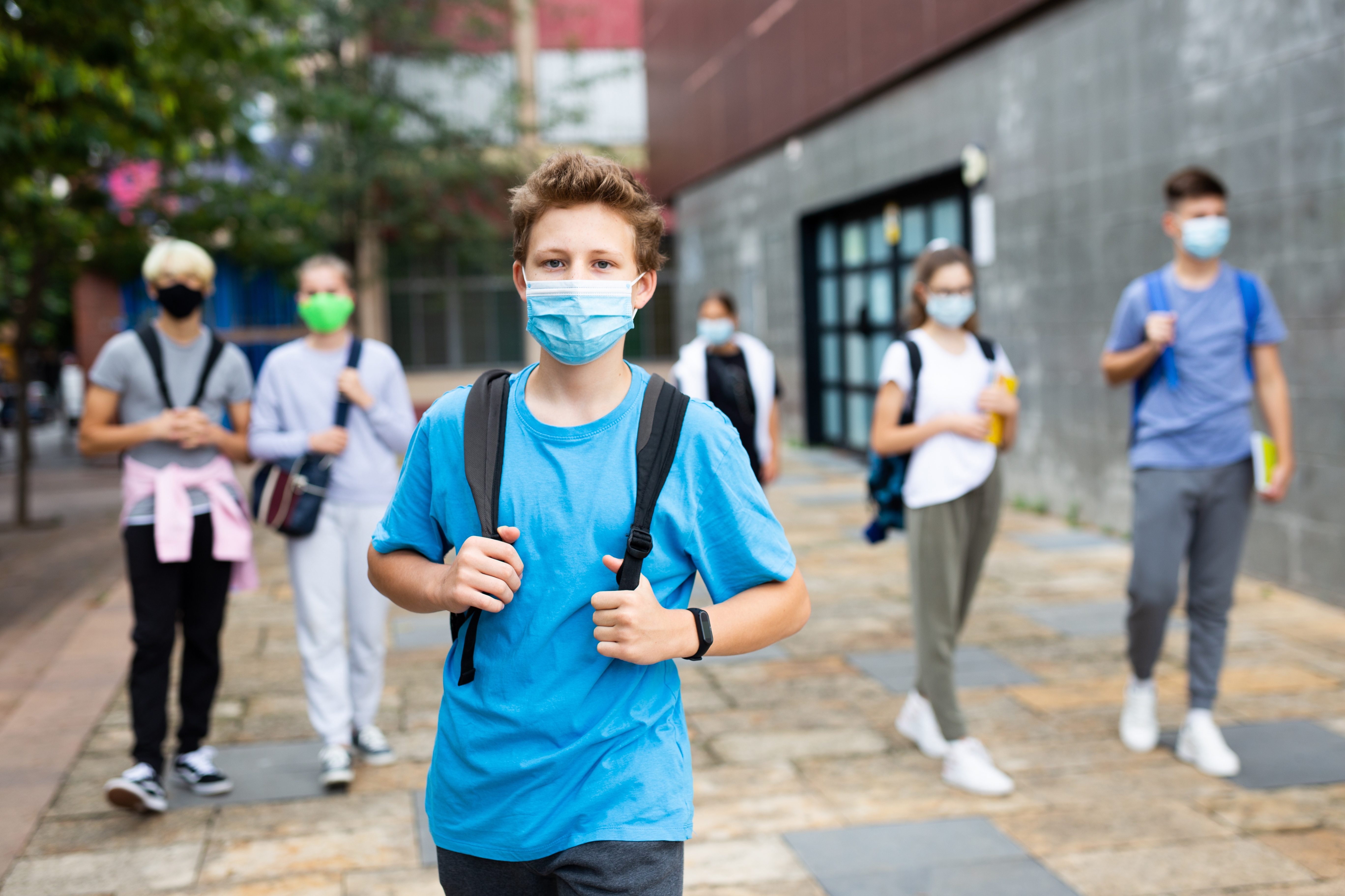 Teenager in protective mask going to school in autumn