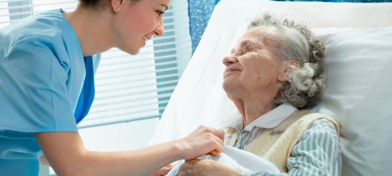 Nurse cares for a elderly woman lying in bed