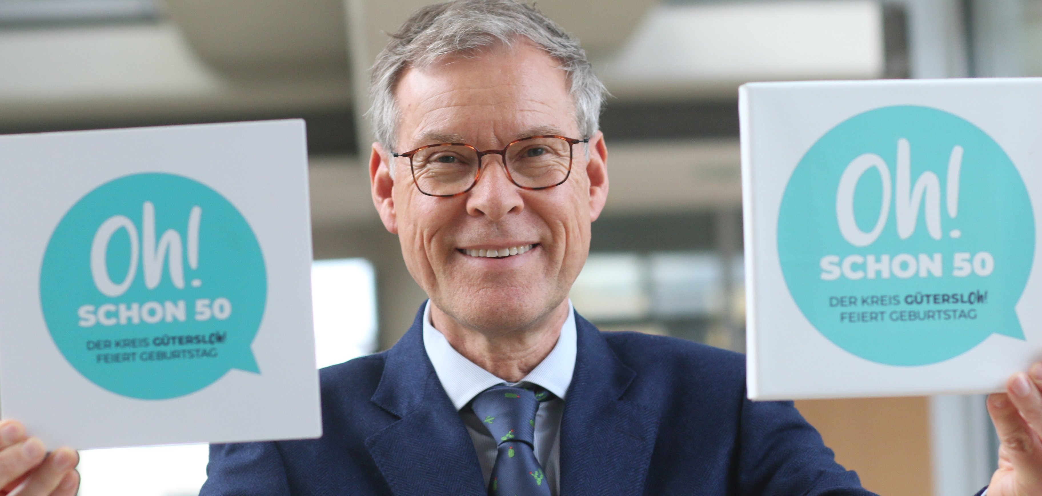 Landrat Adenauer und das Jubiläumslogo zu 50 Jahre Kreis Gütersloh