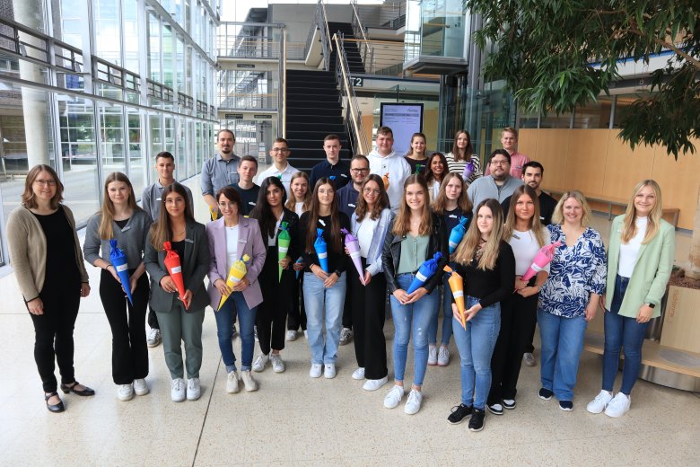 Gruppe von 26 neuen Azubis steht im Foyer des Kreishauses Gütersloh. In den Händen halten sie kleine Schultüten.