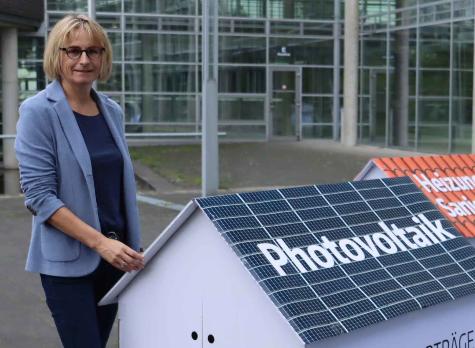 Altbauneu: Frau Thering vor einem Hausmodell mit Photovoltaik