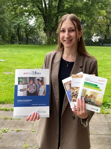 Junge Frau mit Infomaterial zu klimafreundlichen Heizungen in den Händen. 