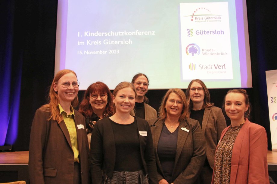 Die Organisatoren und Verantwortlichen kurz vor der Eröffnung der ersten Kinderschutzkonferenz in der Stadthalle Gütersloh (v.l.): Berit Rürup (Netzwerkkoordinatorin Stadt Verl), Michaela Hartmann (Netzwerkkoordinatorin Stadt Gütersloh), Lisa Hoffmeister (Netzwerkkoordinatorin Stadt Rheda-Wiedenbrück), Andreas Reinhold (Fachbereichsleiter Jugend und Familie Stadt Gütersloh), Ilona Overath (Abteilungsleiterin Jugend Kreis Gütersloh), Kreisdirektorin Susanne Koch und Ines Szepanski (Netzwerkkoordinatorin Kreis Gütersloh). Berit Rürup hielt den Eröffnungsvortrag ‚Kinderschutz ohne Grenzen‘.  