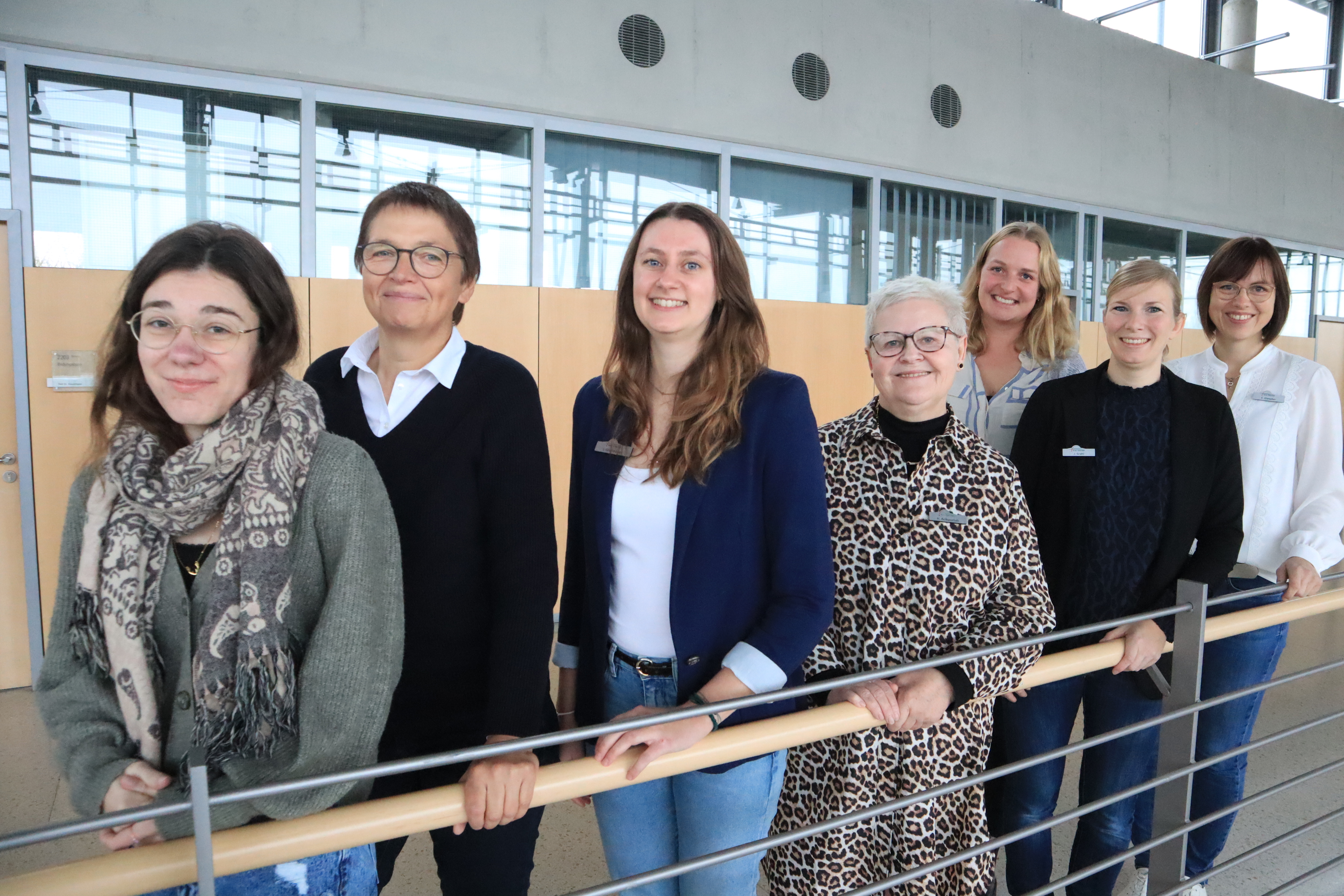 Sieben Personen stehen nebeneinander im Kreishaus Gütersloh und schauen in die Kamera.