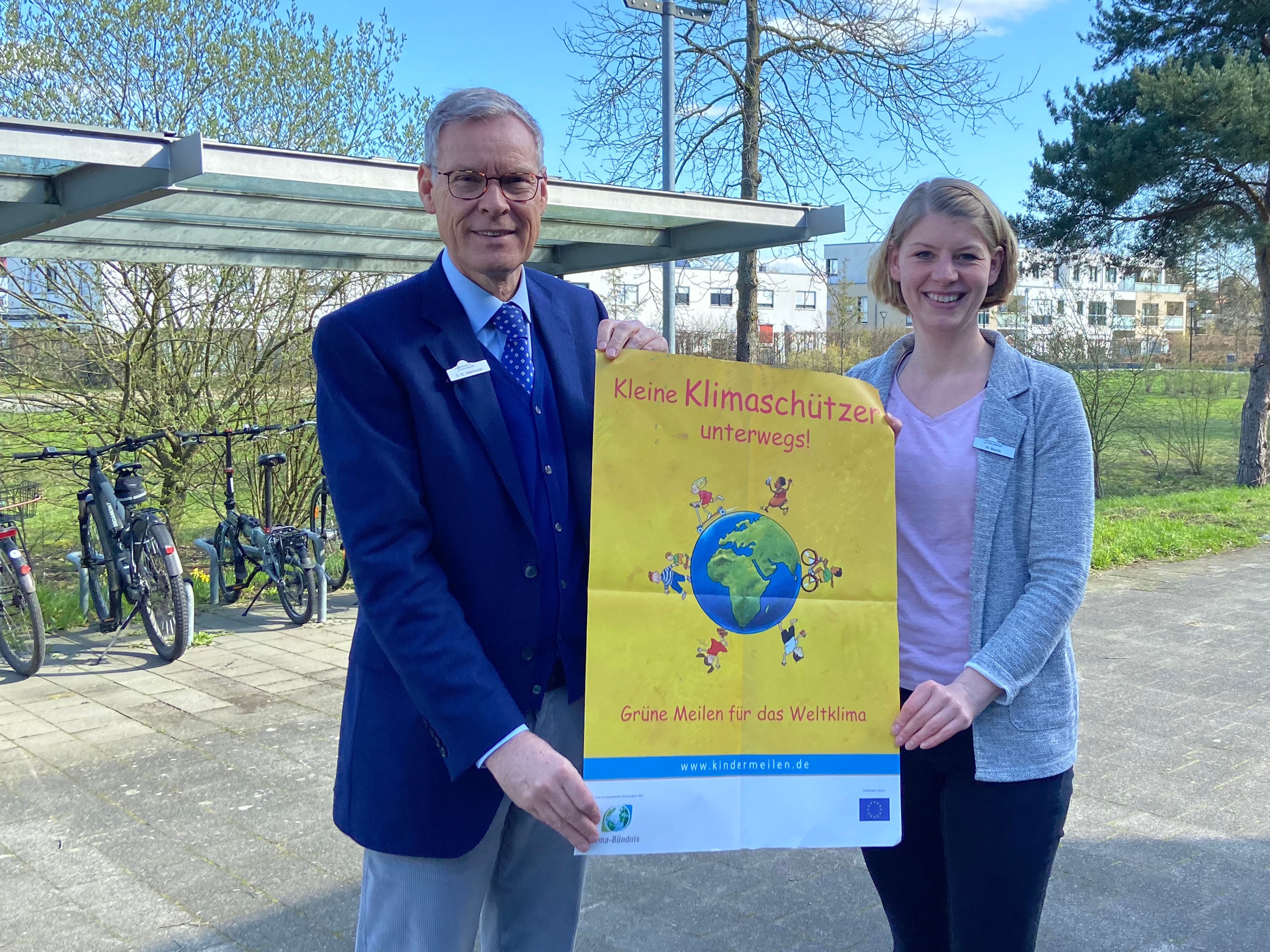 Landrat Sven-Georg Adenauer und die Mobilitätsmanagerin Hanna Bante halten das Plakat zur Kindermeilen-Aktion