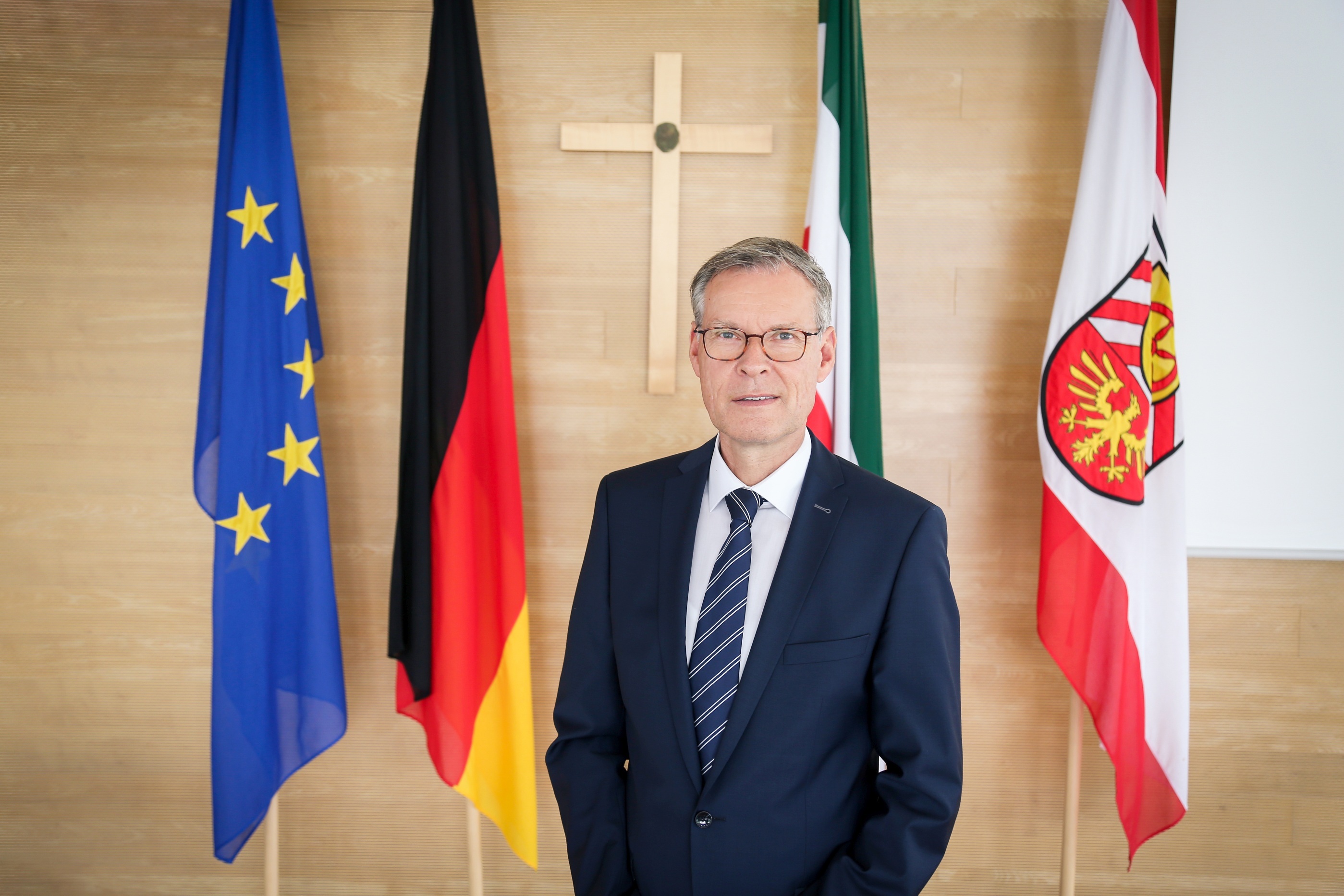 Landrat Sven-Georg Adenauer im Sitzungssaal vor Fahnen Landrat Sven-Georg Adenauer im Sitzungssaal vor Fahnen