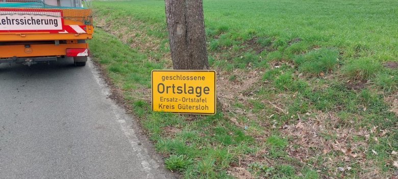 Ortschild ohne Rahmen an Baum angelehnt