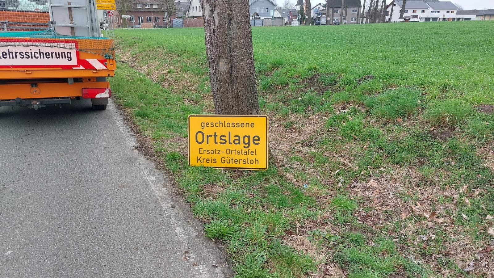 Ortschild ohne Rahmen an Baum angelehnt