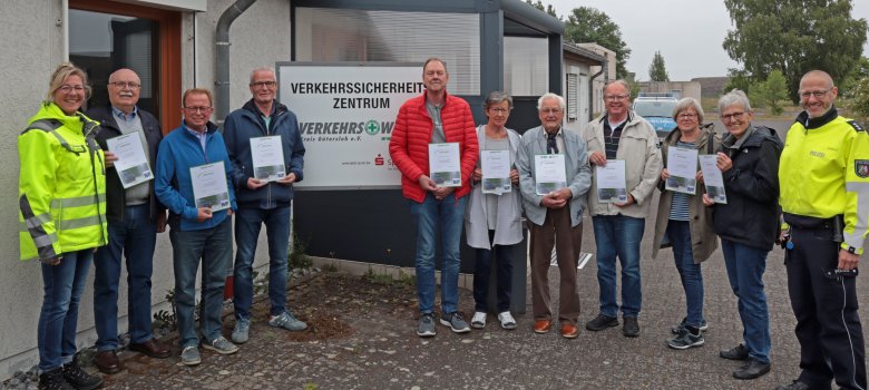 Elf Personenen stehen in einer Reihe. Neun davon halten eine Teilnehmerurkunde in der Hand.