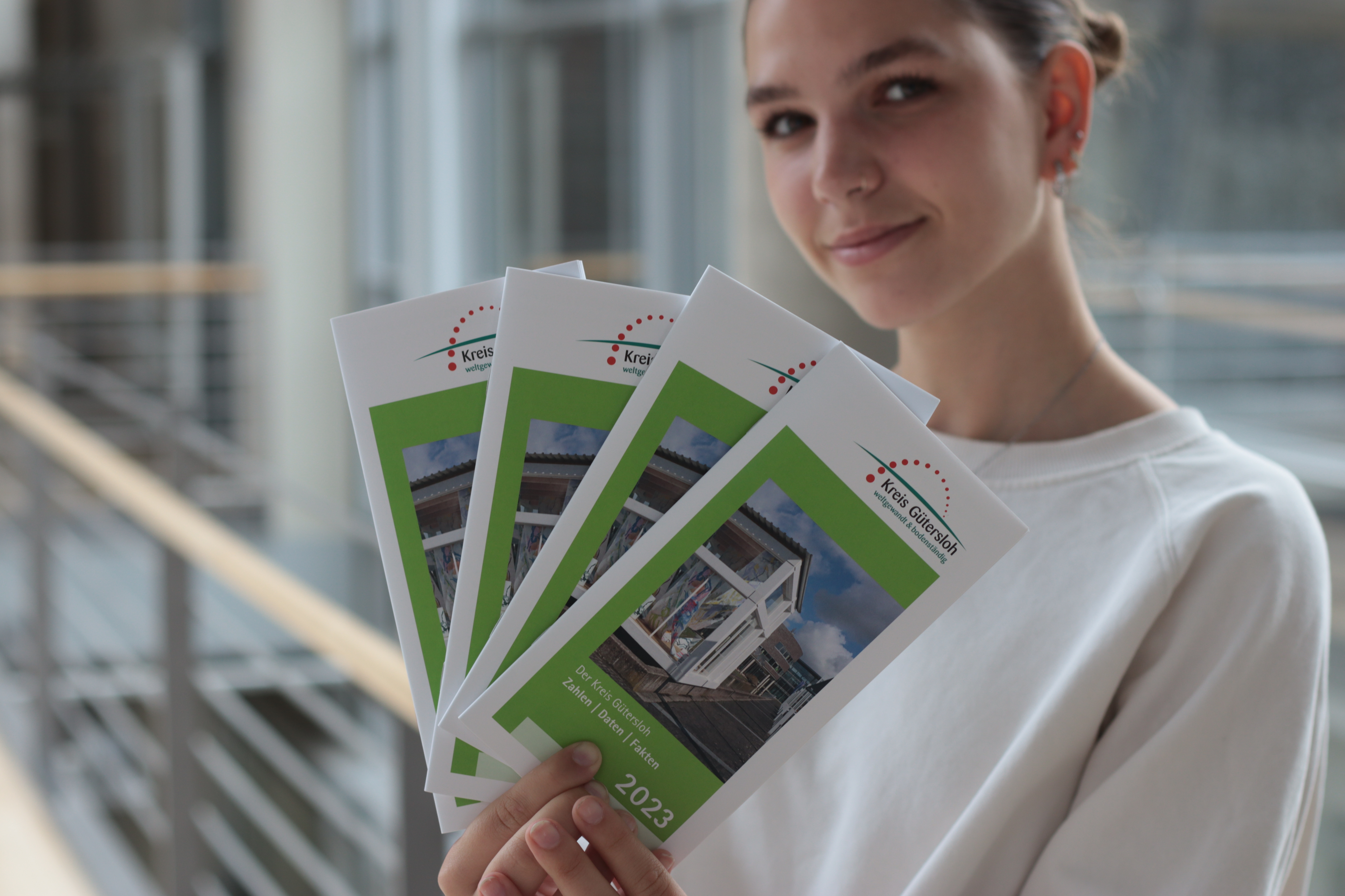 Elín Calmus, die Praktikantin der Pressestelle des Kreises Gütersloh, mit der aktuellen Ausgabe des ‚Zahlen, Daten, Fakten‘ zum Kreis Gütersloh
