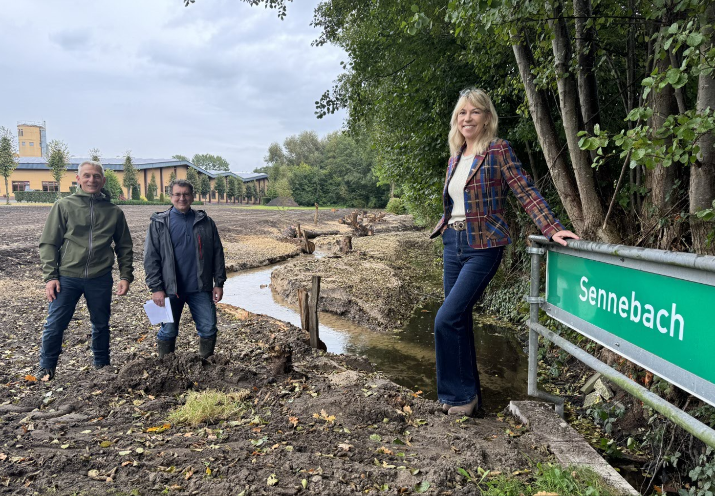 Drei Personen stehen am renaturierten Abschnitt des Sennebachs