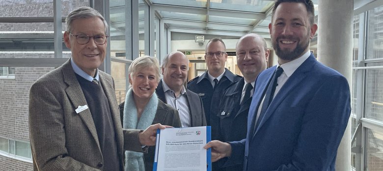 Sechs Personen stehen im Kreishaus Gütersloh mit dem Förderbescheid