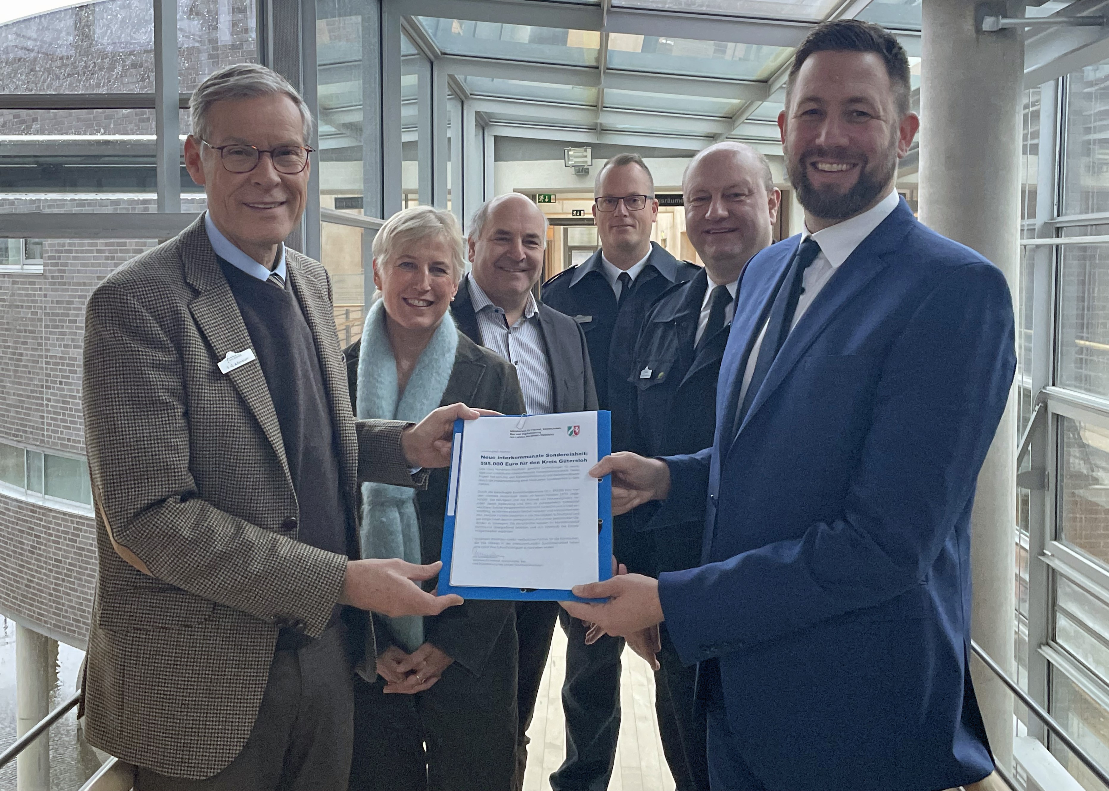 Kreis erhält Förderbescheid vom Land NRW Sechs Personen stehen im Kreishaus Gütersloh mit dem Förderbescheid