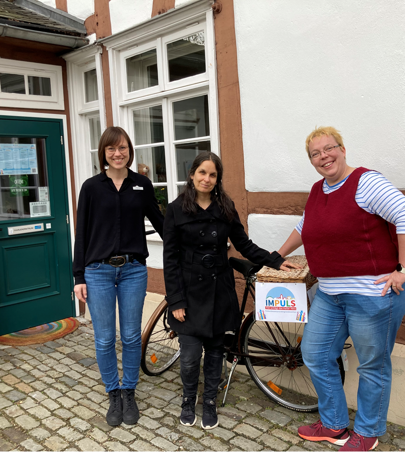 Drei Personen vor einer Häuserfassade