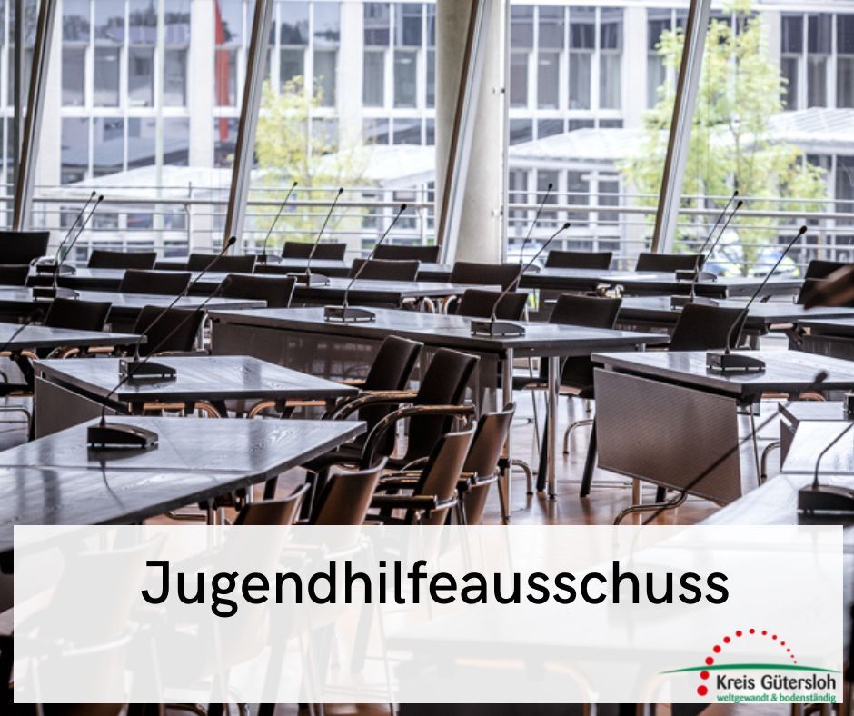 Hinter einem Textbanner mit der Aufschrift 'Jugendhilfeausschuss' ist der Sitzungssaal im Kreishaus Gütersloh zu sehen. 