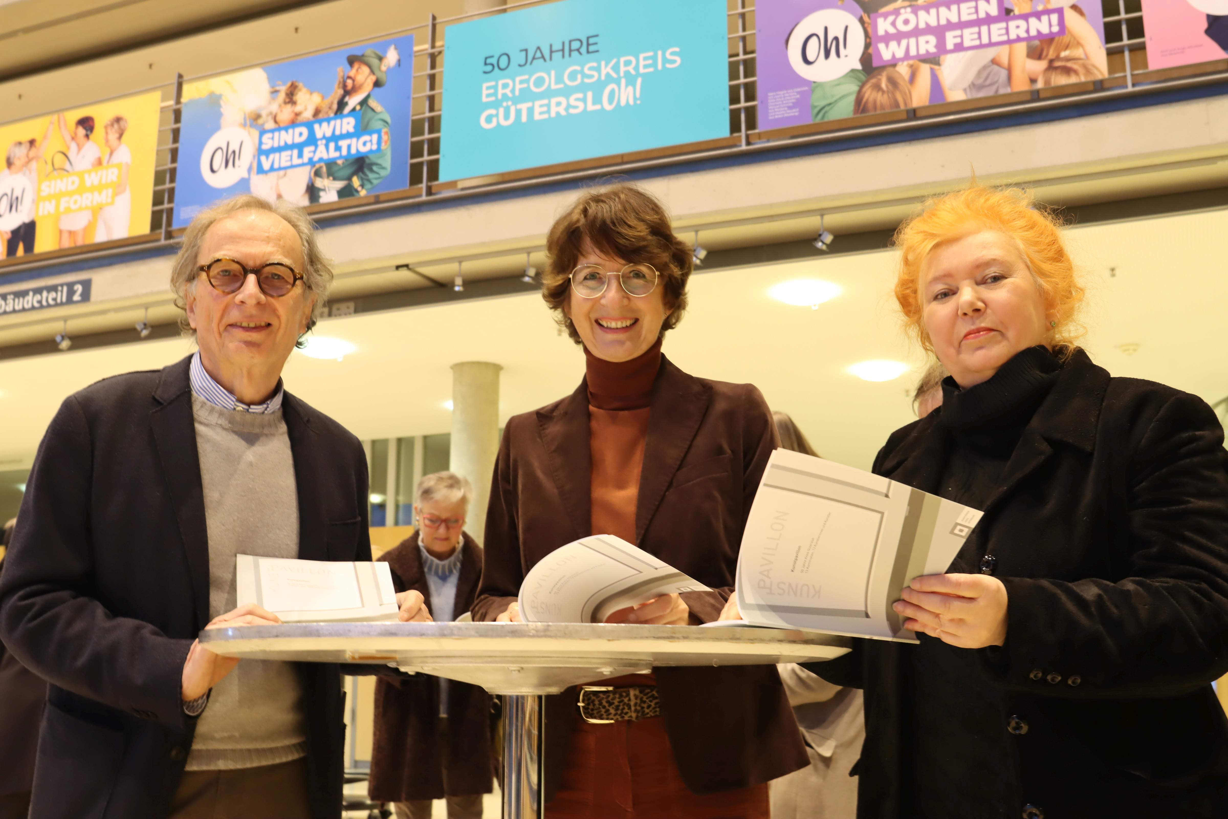Friedrich-Wilhelm Schröder, Vorsitzender des Kunstvereins für den Kreis Gütersloh, Dr. Christine Disselkamp, stellvertretende Landrätin, und Beate Freier-Bongaertz (r.) vom Vorstand des Kunstvereins mit dem Katalog zur Ausstellungsreihe Kunst im Kubus.