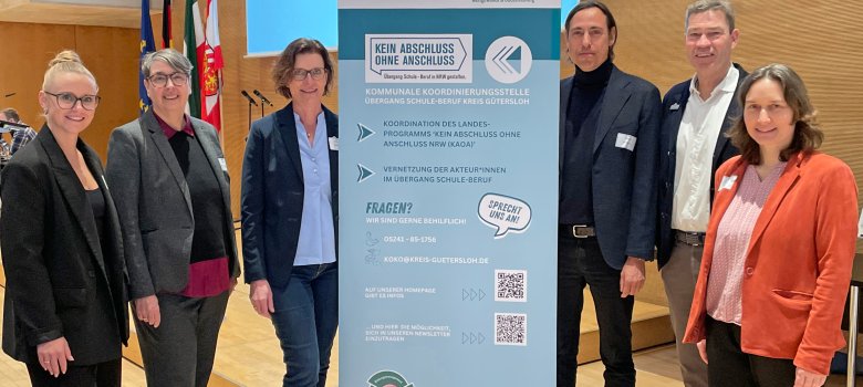 Personen stehen nebeneinander und blicken in die Kamera.