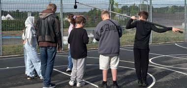 Kinder filmen auf einem Sportplatz