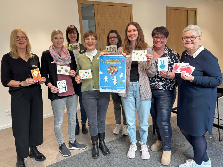 Personen stehen nebeneinander und halten Postkarten in den Händen.