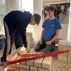 Zwei Personen bauen eine kleine Mauer