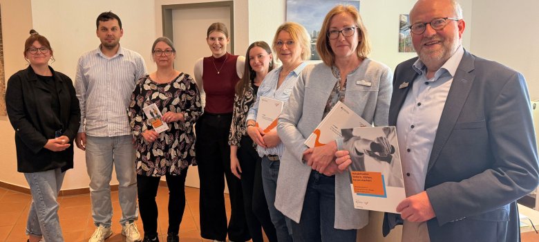 Personen stehen nebeneinander und halten teilweise Infomaterial in den Händen. 