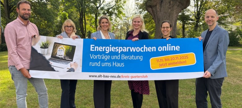 Personen stehen nebeneinander und halten einen Banner in der Hand. 