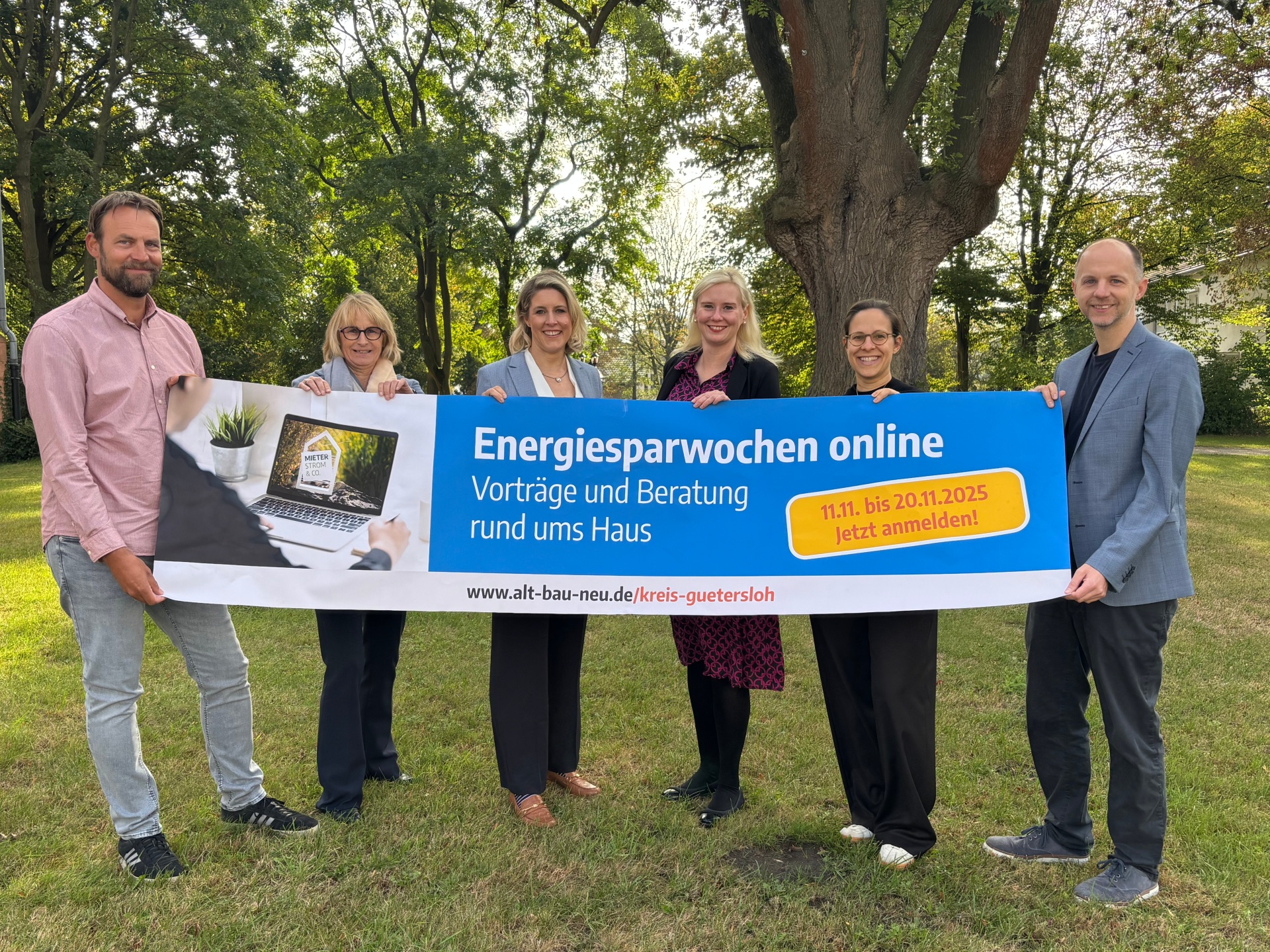 Personen stehen nebeneinander und halten einen Banner in der Hand. 