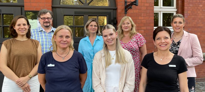 Personen stehen nebeneinaner vor dem Eingag der VHS Gütersloh.