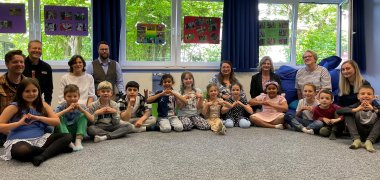 Die teilnehmenden Kinder und die Projektverantwortlichen sitzen in einer Schulklasse. In dem Raum fand auch die Aufführung statt.