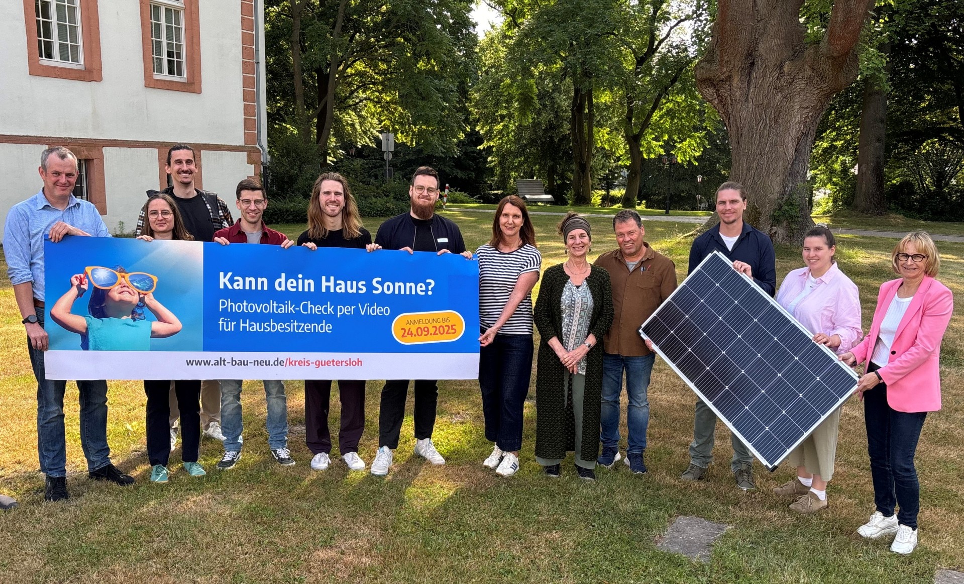 Personen stehen nebeneinander und halten Plakate und Banner in den Händen. 