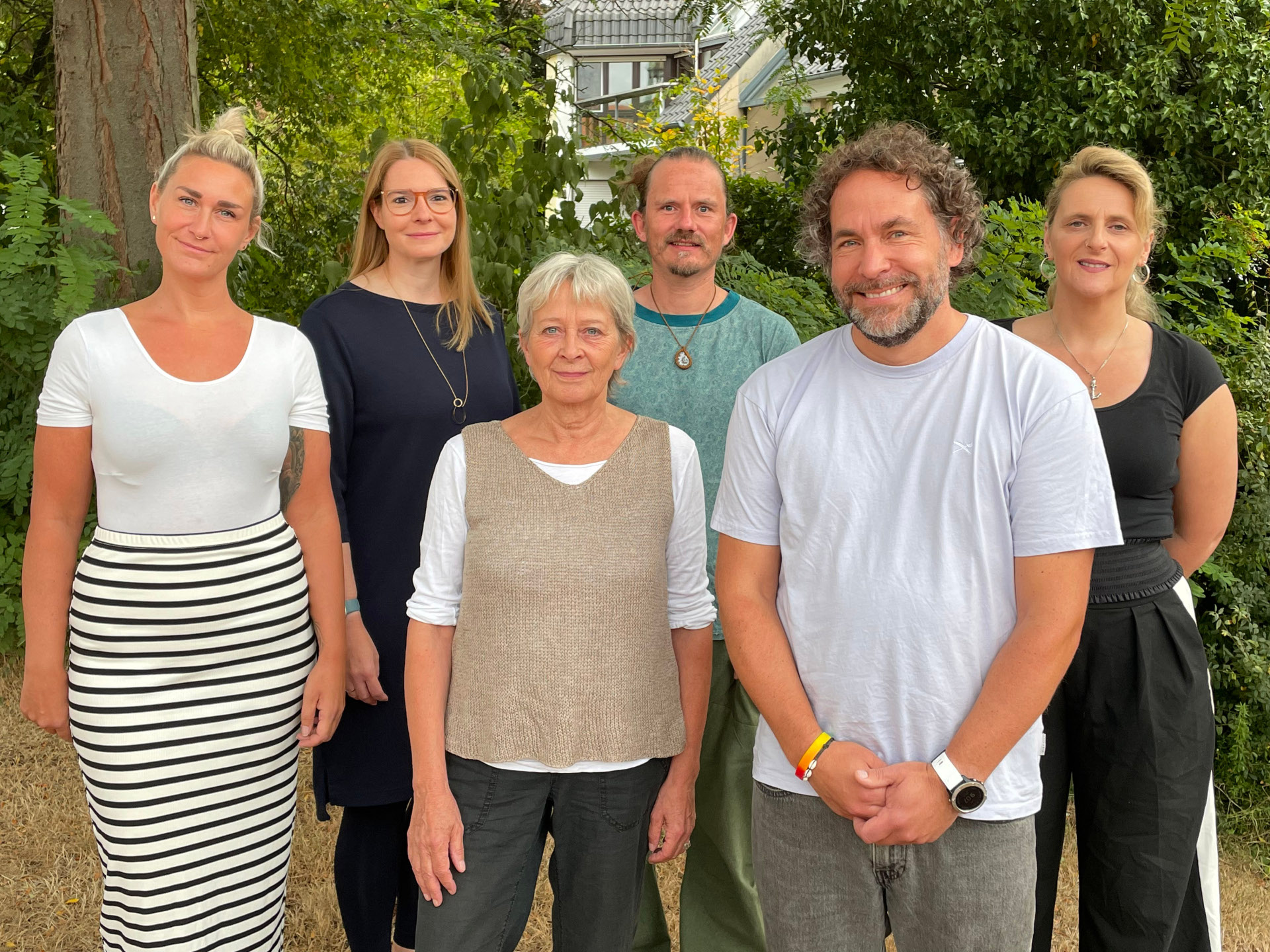 Personen stehen nebeneinander und blicken in die Kamera. 