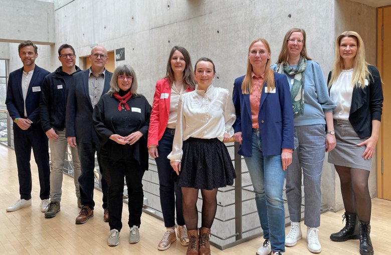 Personen stehen nebeneinander und blick in die Kamera. 