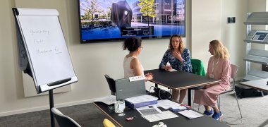 Eine Person im Gespräch mit zwei weiteren Personen.