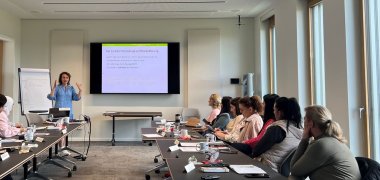 Eine Person erklärt einer Gruppe von Menschen etwas