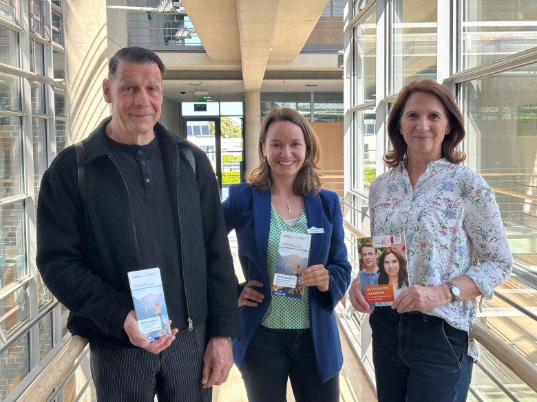 Drei Personen mit Flyern in der Hand