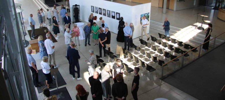 Blick aus der ersten Etage ins Foyer des Kreishauses Gütersloh. Zu sehen sind Ausstellungswände mit den Kunstwerken sowie Schaufensterpuppen mit Textilentwürfen. 