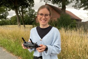 Praktikantin Jeanne Dölwes bei einem Drohnenflug. Praktikantin Jeanne Dölwes mit einem Controller in der Hand, mit dem sie die Drohne fliegt.