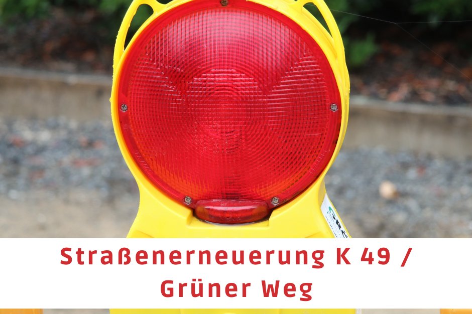 Im Mittelpunkt des Bildes befindet sich der obere Teil einer Absperrbake. Auf einem Textfeld steht "Straßenerneuerung K 49 / Grüner Weg"