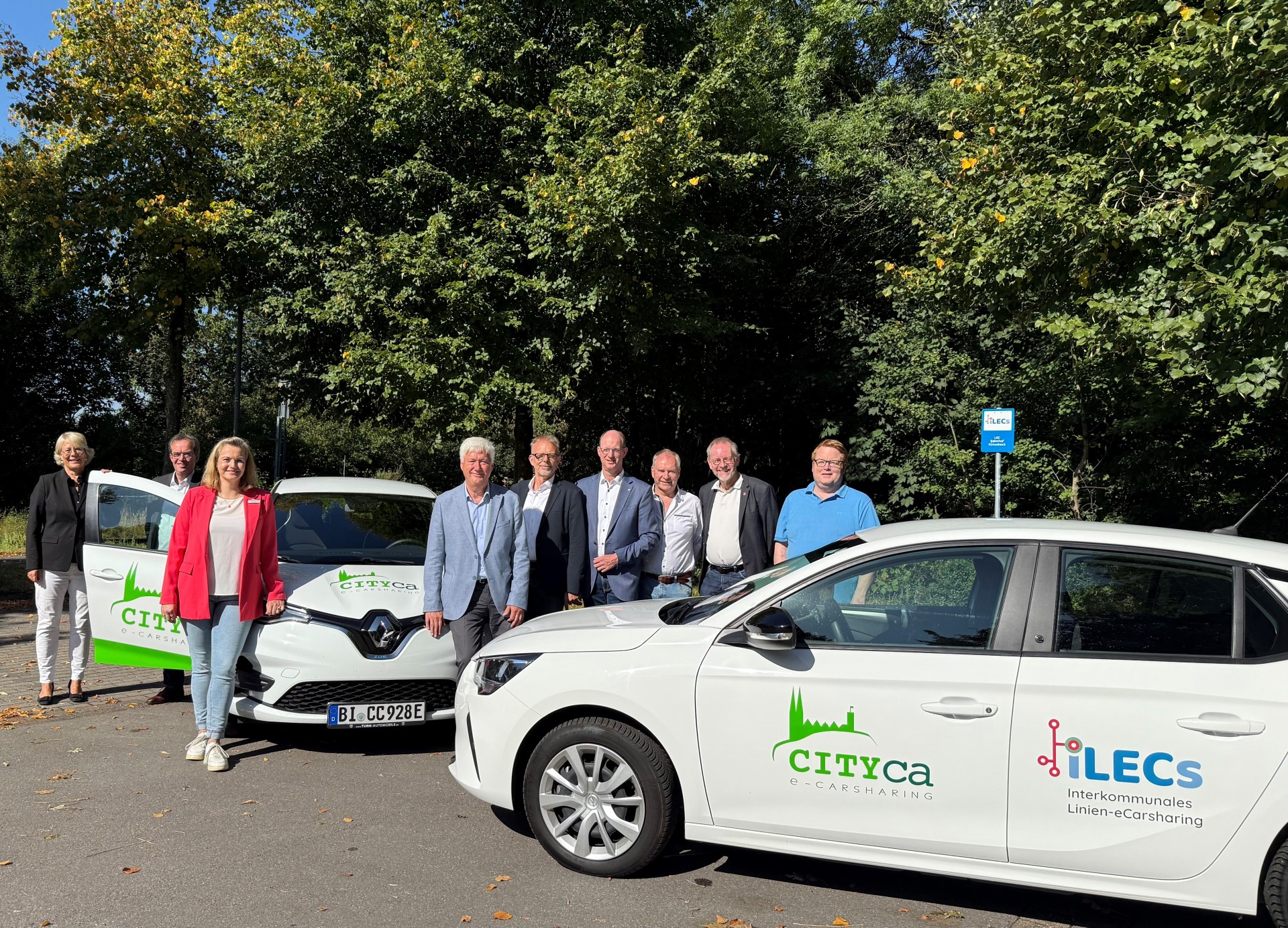 Projektpartner stehen an den zwei E-Autos.