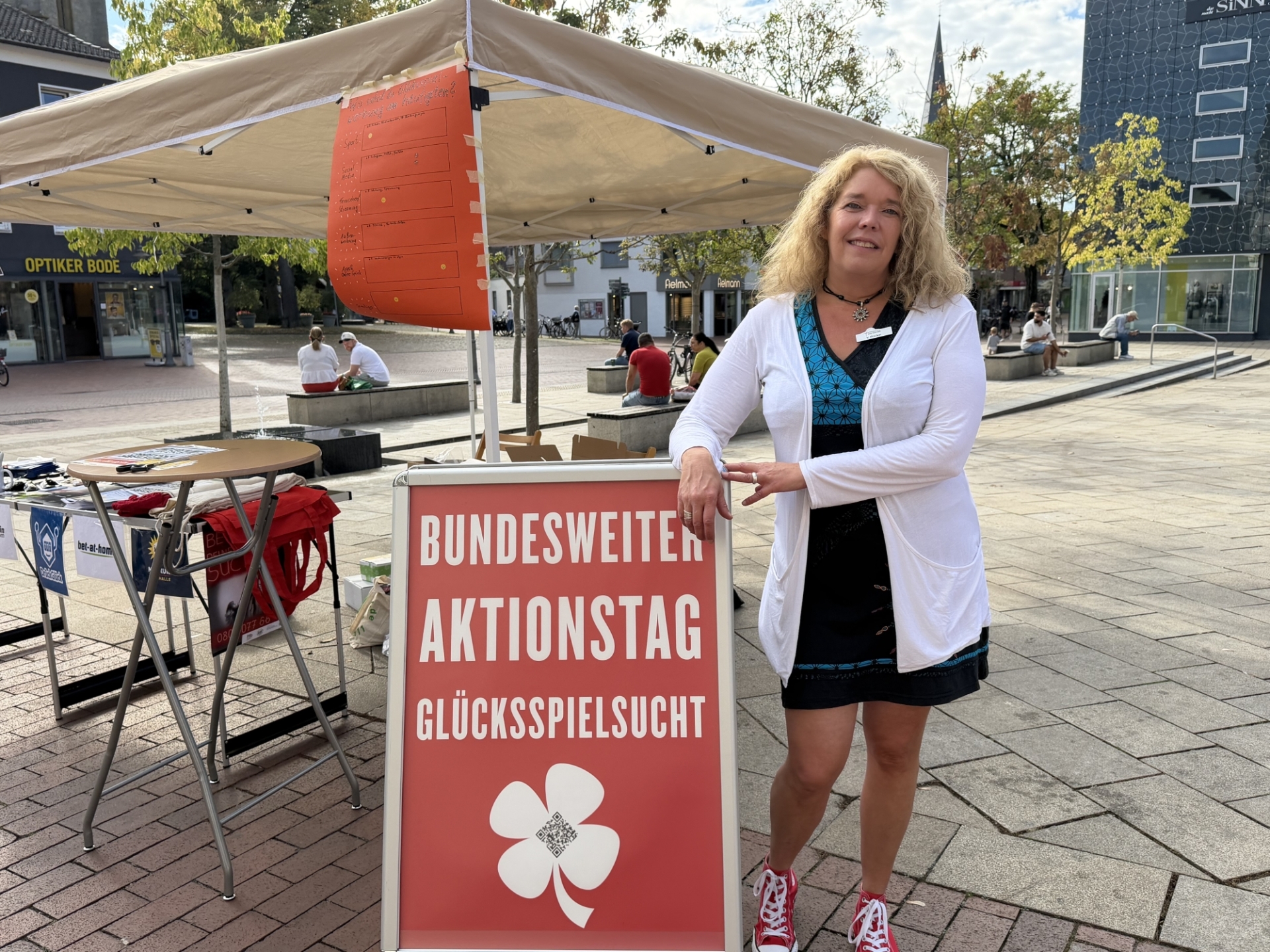 Frau steht an einem Aufsteller und blickt in die Kamera.