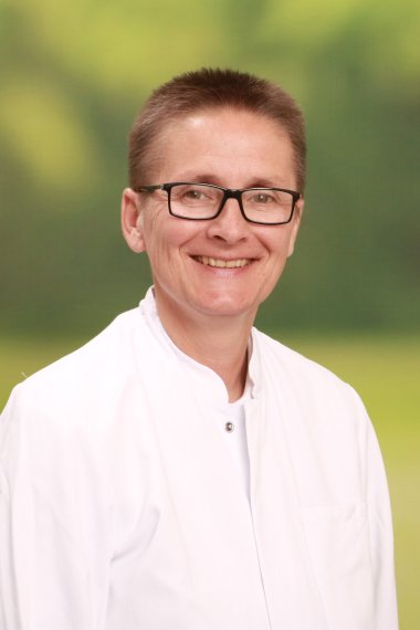 Ärztin im weißen Kittel, blickt in die Kamera