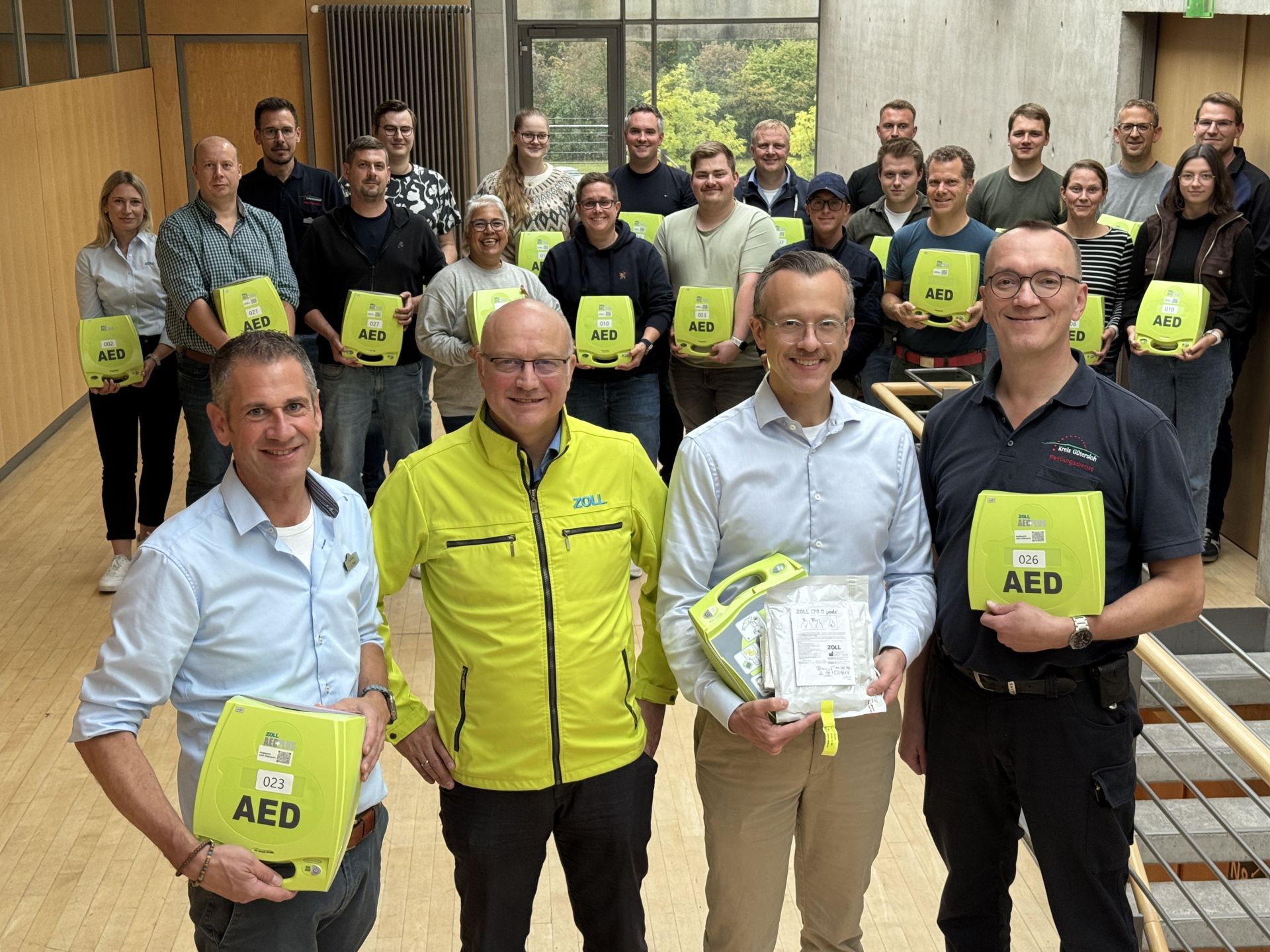 Defis für die Mobilen Retter Die ersten Mobilen Retter - hier im Hintergrund des Fotos zu sehen - haben ihre ‚Automatisierten Externen Defibrillatoren (AED)‘ erhalten, im Vordergrund (v.l.): Jürgen Theis (Leiter der Abteilung Bevölkerungsschutz), Andreas Cleve (Stiftung ‚Zoll Foundation‘), Dr. Gerrit Jansen (Leiter der Studie) und Dr. Bernd Strickmann (Ärztlicher Leiter Rettungsdienst Kreis Gütersloh).