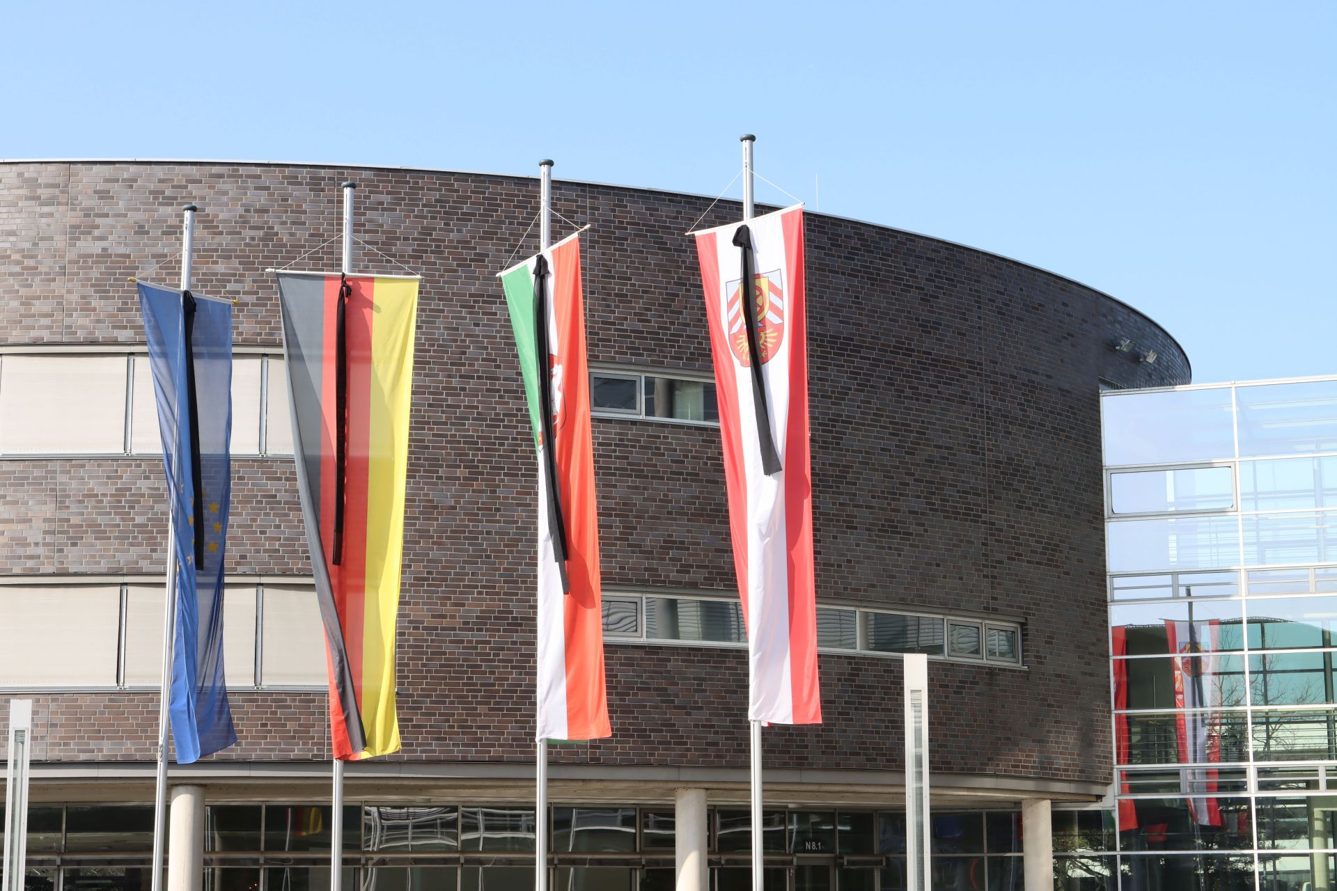 Flaggen vor dem Kreishaus Gütersloh auf Hochmast. An jeder Flagge hängt ein schwarzer Trauerflor.