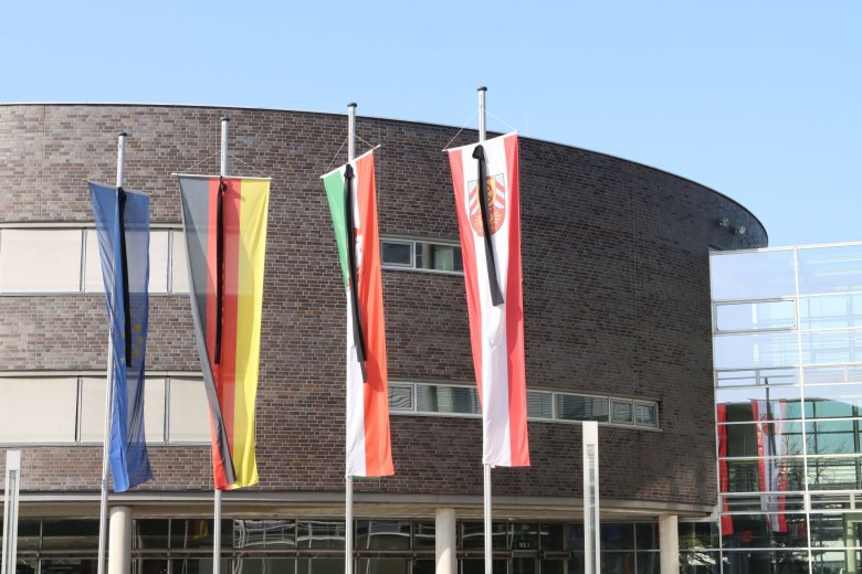 Flaggen vor dem Kreishaus Gütersloh auf Hochmast. An jeder Flagge hängt ein schwarzer Trauerflor. 