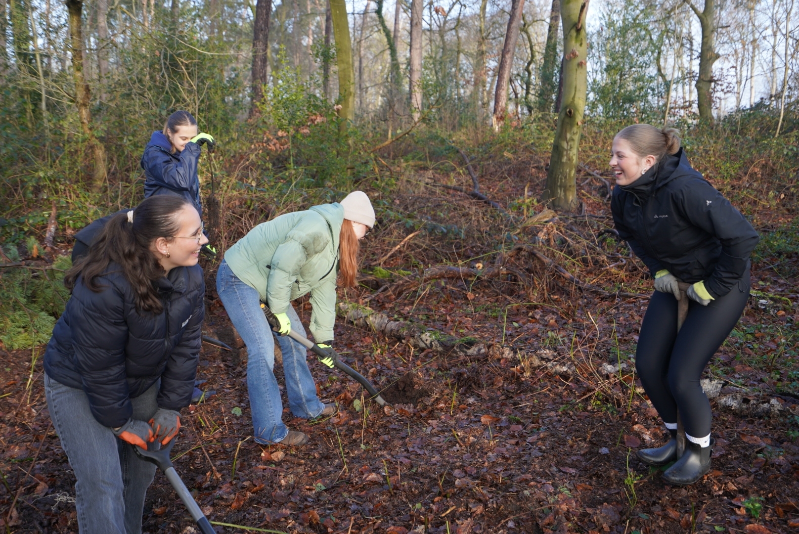 Schülerinnen graben in der Erde mit einem Spaten.