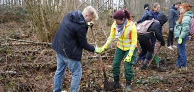 Frau hilft einem Schüler beim Graben eines Pflanzplatzes.